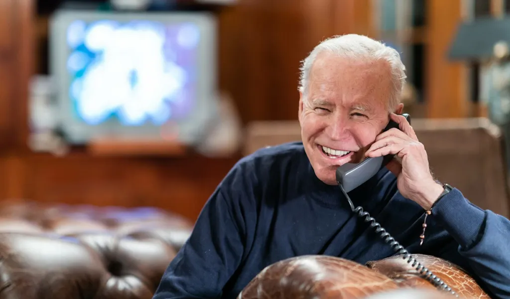 Joe Biden lacht während eines Telefonats.