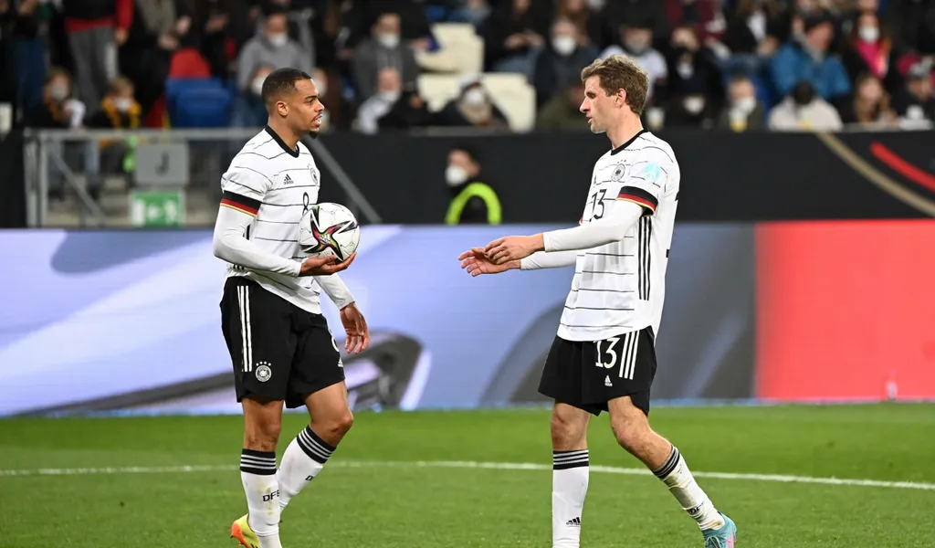 Lukas Nmecha gibt Thomas Müller vor einem Strafstoß den Ball.