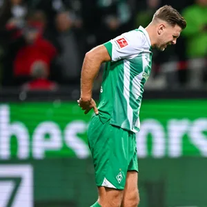 Niclas Füllkrug fasst sich mit schmerzverzerrtem Gesicht an den Rücken