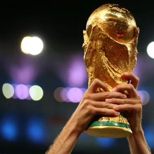 Ein Fußballspieler stemmt den WM-Pokal in die Lüfte