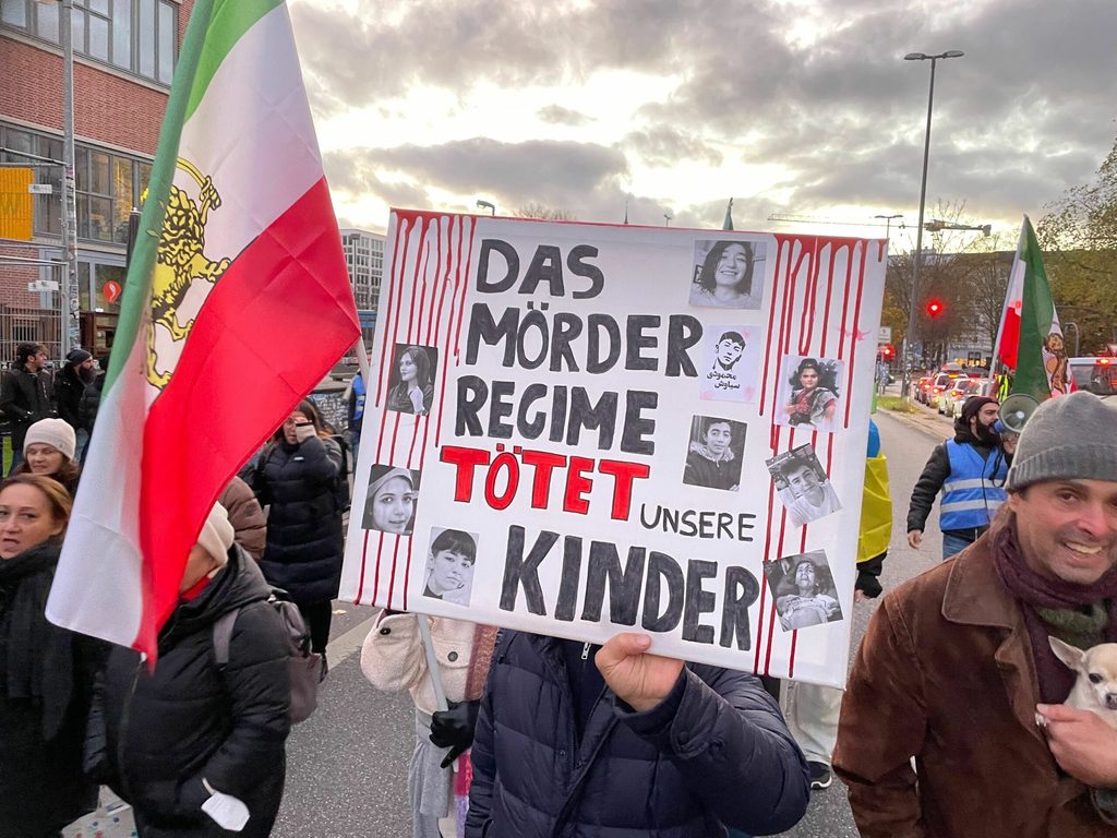 „Das Mörder Regime tötet unsere Kinder“ steht auf einem Plakat.