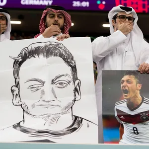 Katarer zeigen Özil-Bilder und die Mund-zu-Geste.