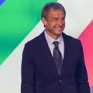 Jürgen Klinsmann steht im Anzug auf der Bühne