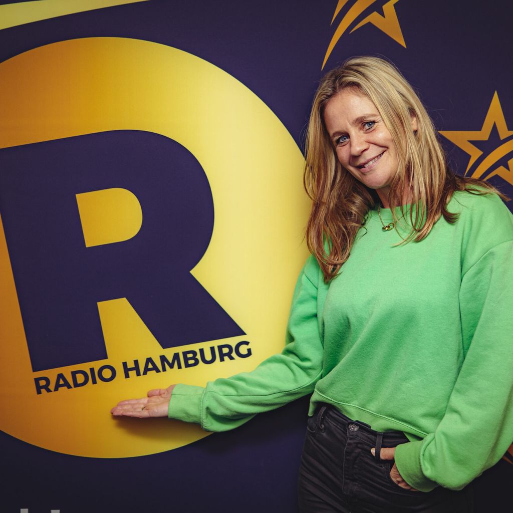 Jacqueline „Jacky“ Kovacevic steht vor einem Plakat bei „Radio Hamburg“.