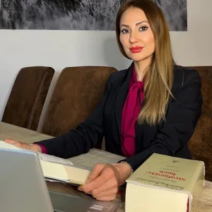 Jacqueline Ahmadi sitzt an einem Tisch vor einem Bild von einem Löwen.