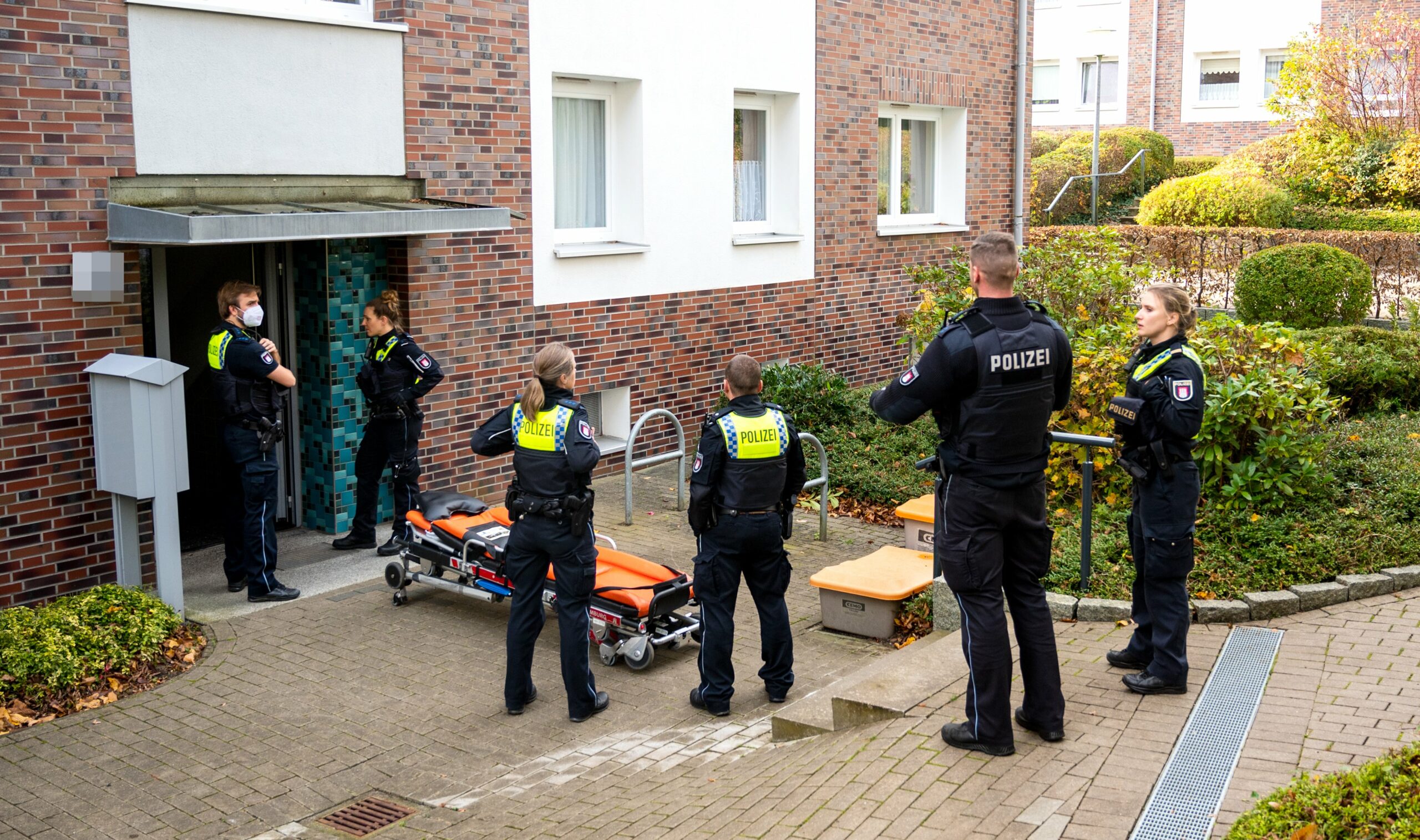 Polizeibeamte stehen vor einem Mehrfamilienhaus in Lohbrügge, wo eine Frau erstochen wurde