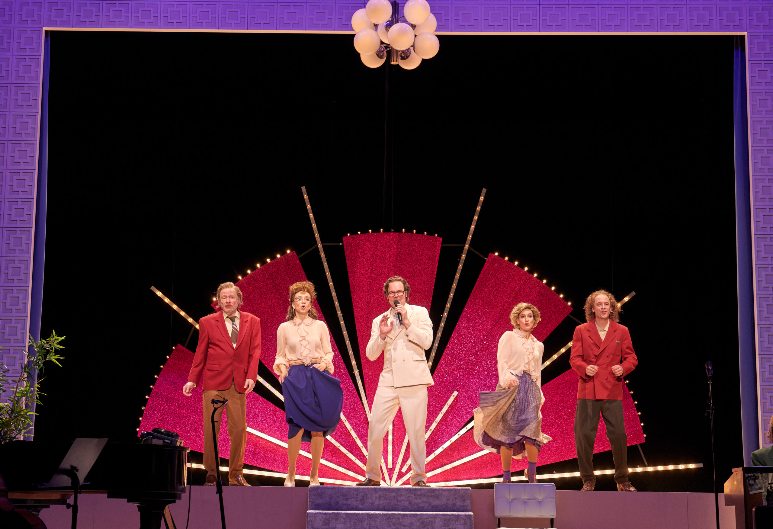 Fünf Menschen singen und tanzen auf der Bühne