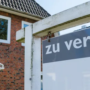 Ein Haus, davor ein Schild „zu verkaufen“