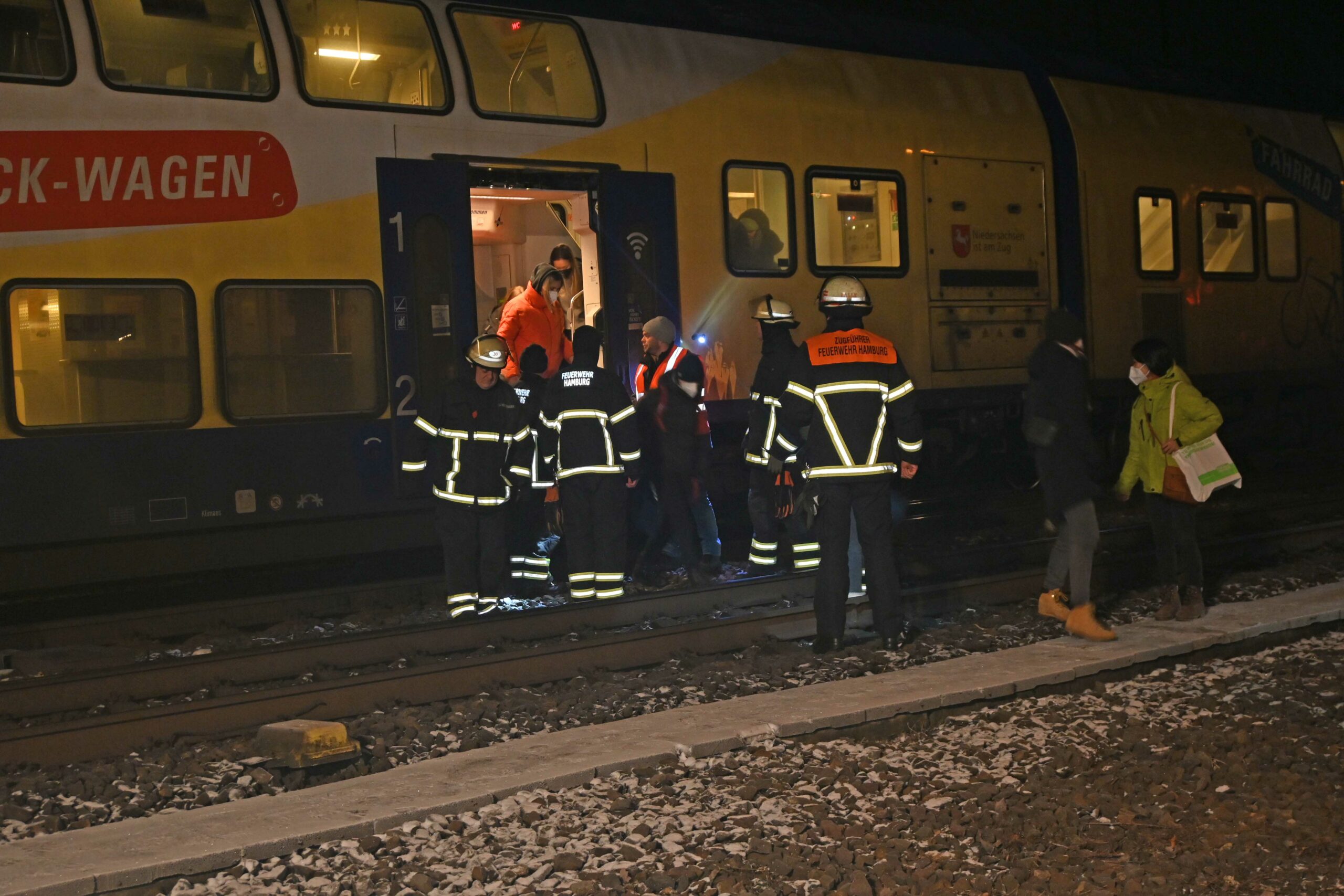 Feuerwehrkräfte führen die Fahrgäste aus dem Zug.
