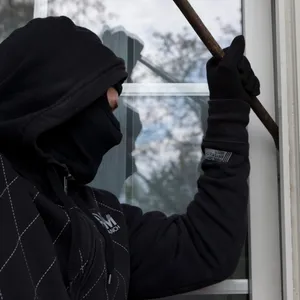 Ein Einbrecher an einer Fensterscheibe