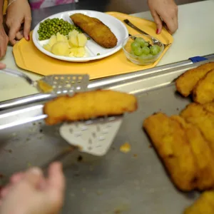 Ein Kind lädt sich Fisch auf den Teller