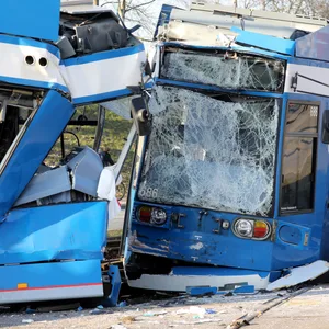 Zwei zusammengestoßene Straßenbahnen, davor ein Polizist