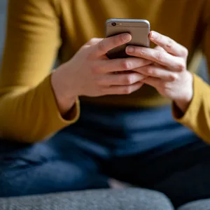 Eine junge Frau hält ein Smartphone in der Hand.