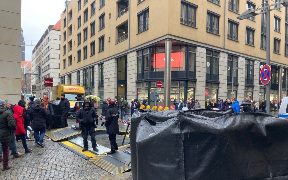 Menschen und Mitarbeiter eines Sicherheitsunternehmens stehen in der Nähe der Altmarktgalerie nach einer Geiselnahme.