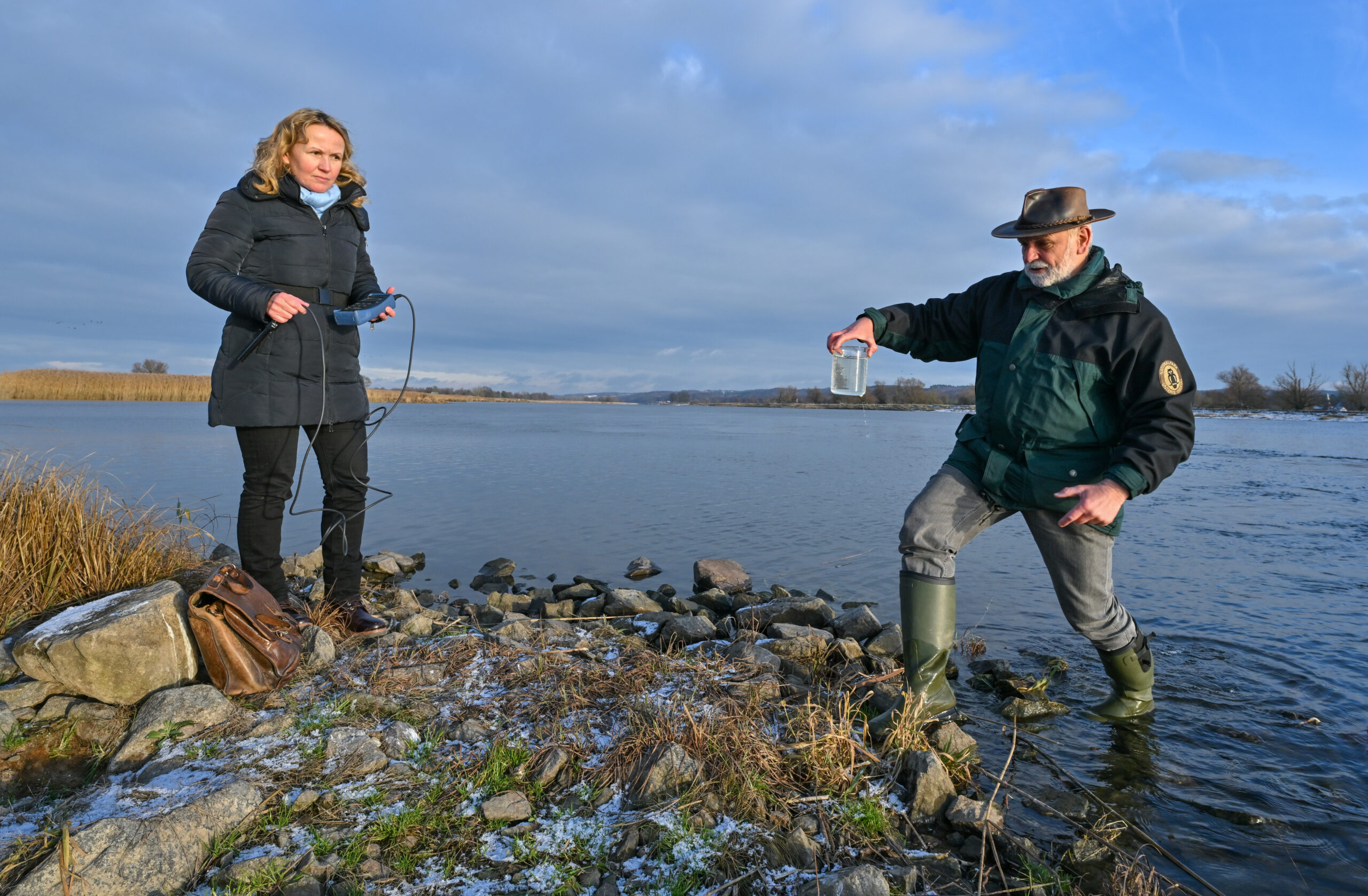 Michael Tautenhahn, stellvertretender Leiter Nationalpark Unteres Odertal, untersucht das Oderwasser. Bundesumweltministerin Steffi Lemke (Grüne) begleitet ihn.