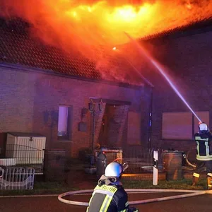 Feuerwehrleute löschen das brennende Dach.