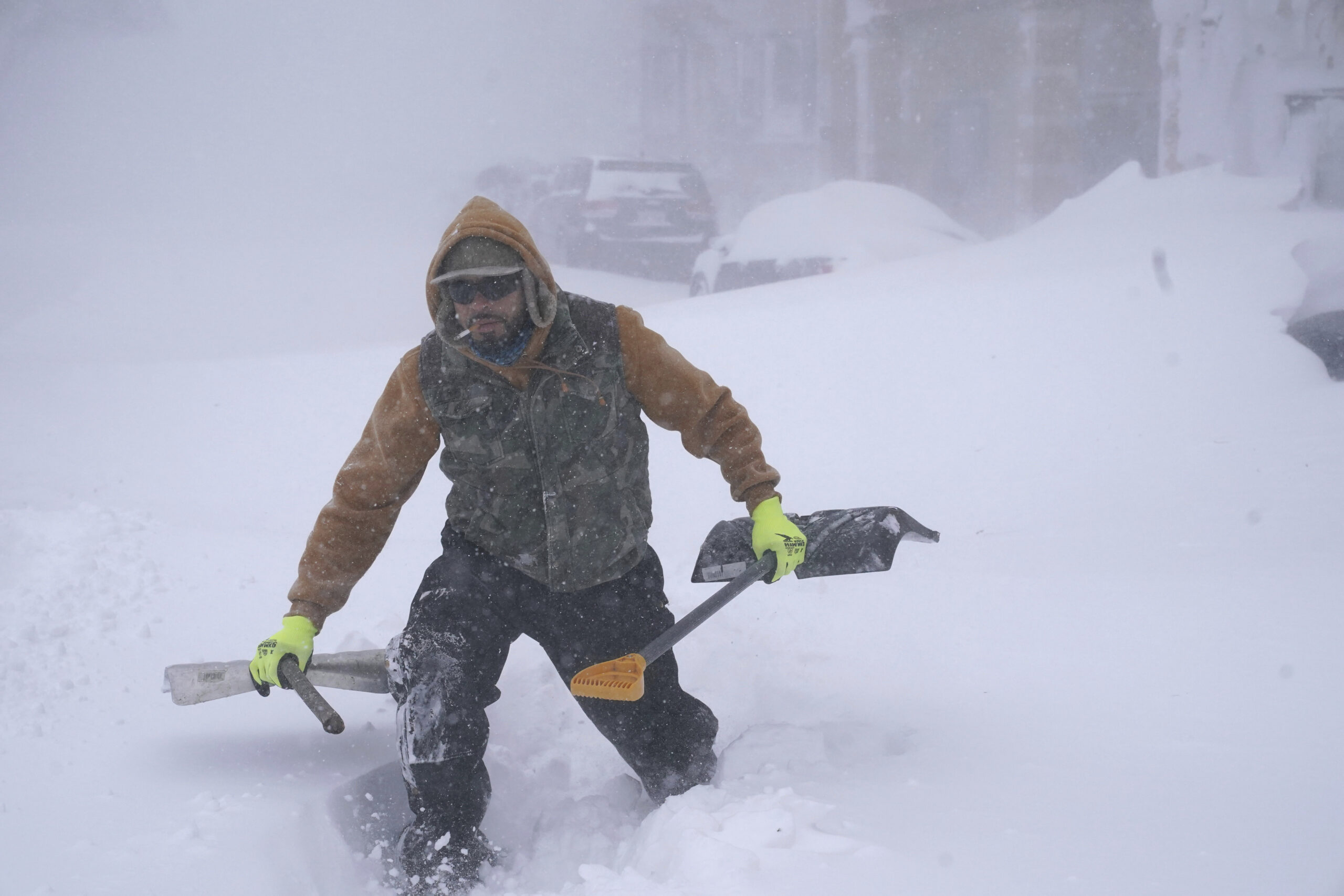 In Buffallo im Bundesstaat New York lag bis zu 70 Zentimeter Schnee. Travis Sanchez stapft mit zwei Schaufeln über eine Schneewehe, um einen gestrandeten Autofahrer auf der Chenango Street zu helfen.