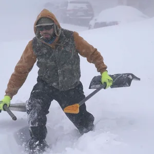 In Buffallo im Bundesstaat New York lag bis zu 70 Zentimeter Schnee. Travis Sanchez stapft mit zwei Schaufeln über eine Schneewehe, um einen gestrandeten Autofahrer auf der Chenango Street zu helfen.