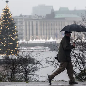 Ein Mann läuft mit Regenschirm um die weihnachtliche Binnenalster