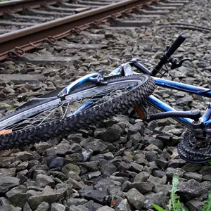 Ein völlig demoliertes Fahrrad liegt neben einem Bahngleis