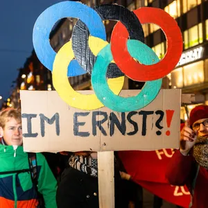 Eine Frau hält ein Schild mit den olympischen Ringen und „Im Ernst“ hoch