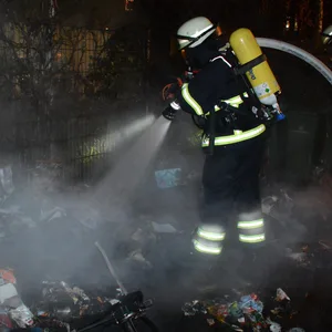 Feuerwehrleute löschen brennende Müllcontainer (Archivbild).