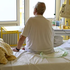 Mann sitzt auf Krankenhausbett