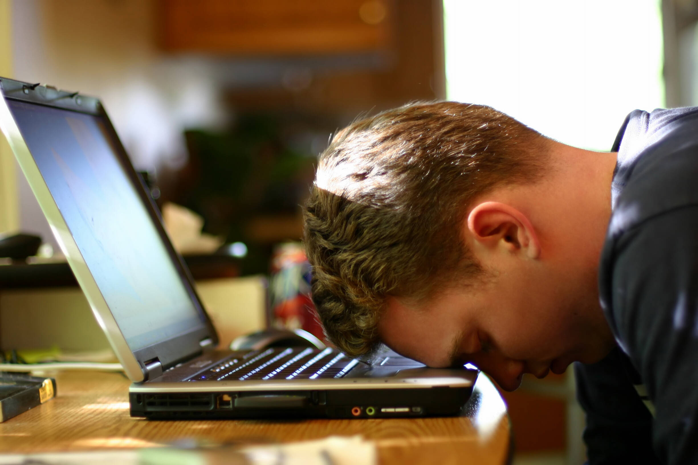 Mann schlägt Kopf auf Laptop