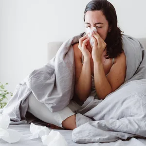 Eine Frau liegt mit Schnupfen im Bett. Immer mehr Menschen rufen wegen Kleinigkeiten beim Notruf an. (Symbolbild)