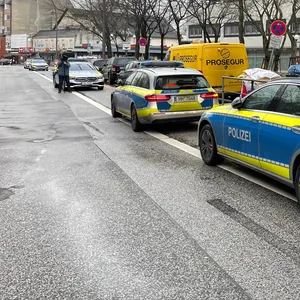 Streifenwagen der Polizei und Fahrzeuge der Feuerwehr am Tatort in Billstedt.