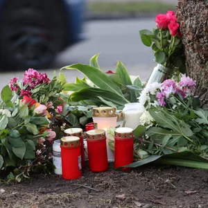 Blumen, Kerzen und Grablichter stehen am Straßenrand an einem Baum, wo am Morgen des 26.12.2022 eine 23-jährige Frau tot gefunden wurde.