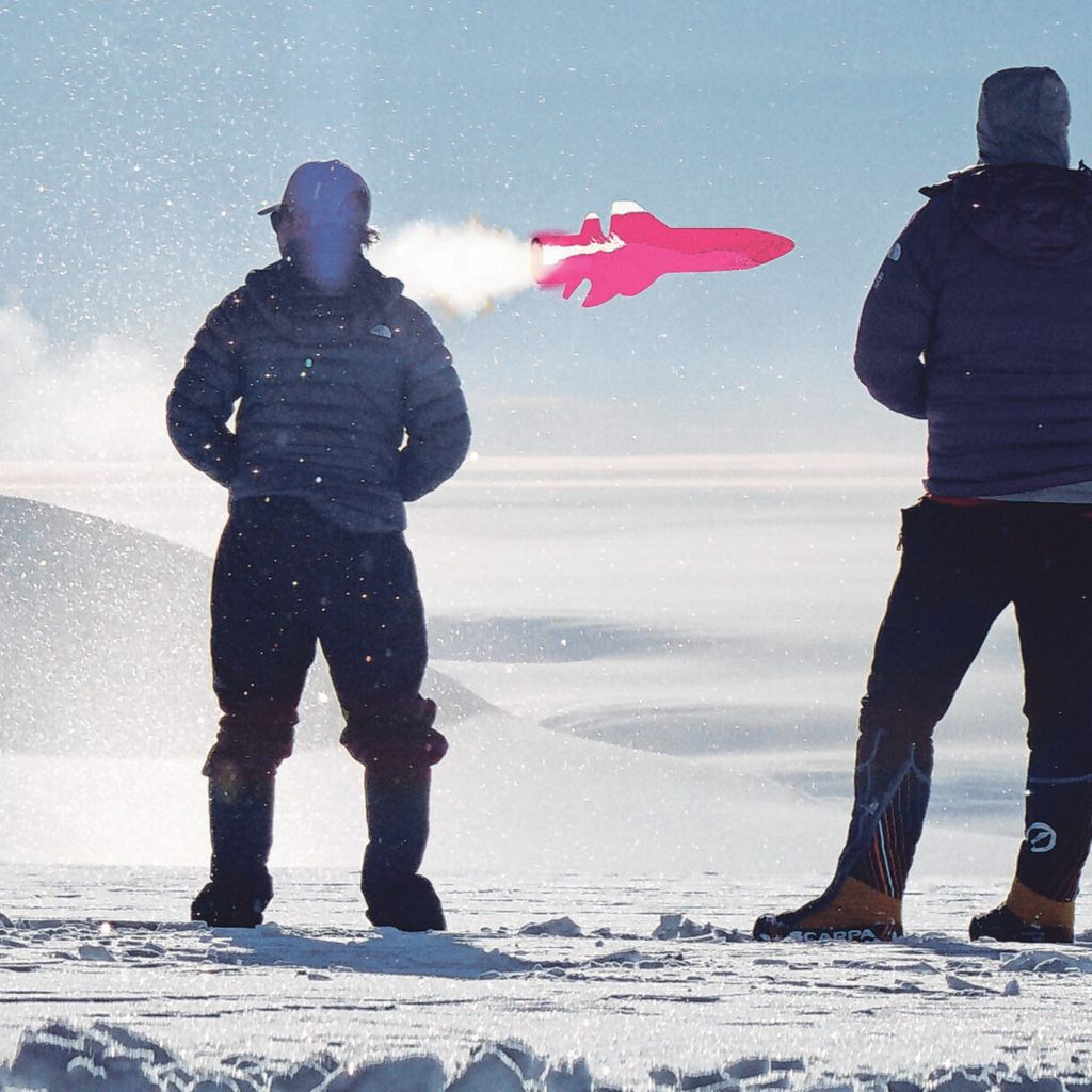 Zwei Männer stehen im Schnee und blicken auf einen rosa Jet.