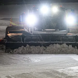 Eine Pistenraupe schiebt Schnee auf einer Skipiste (Symbolbild).