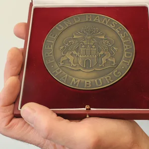 Die massive Bronze-Medaille für „treue Arbeit im Dienste des Volkes“ einem roten Etui mit dem Großen Hamburger Staatswappen