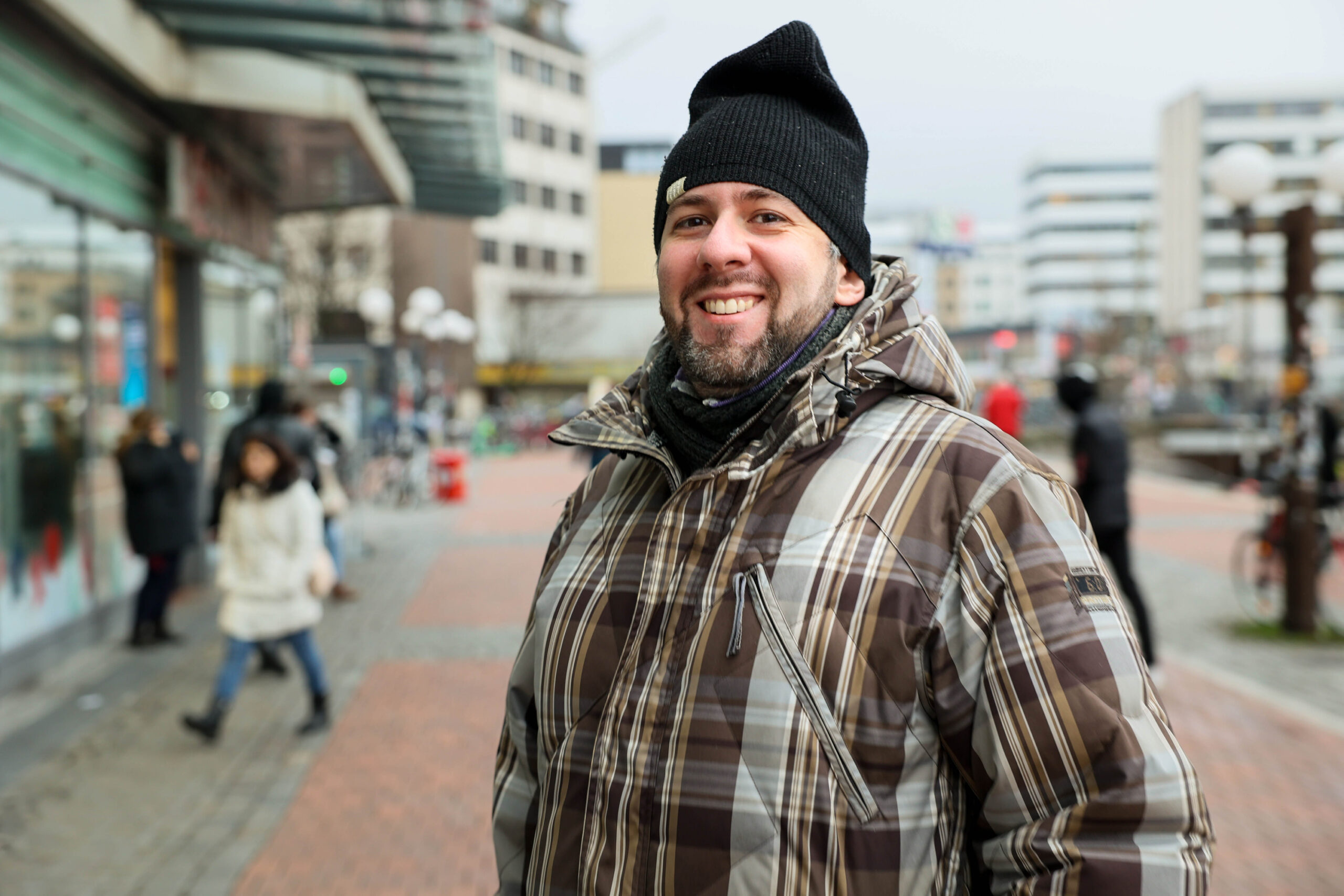 Ein Mann mit einer Mütze steht lächelnd vor dem Altonaer Bahnhof