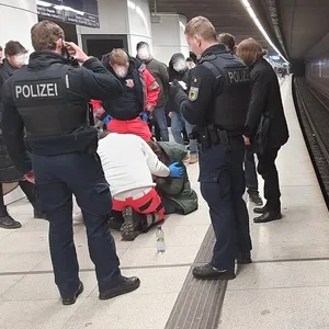 Bundespolizisten und Sanitäter kümmern sich um die auf die Gleise gestürzte Frau.
