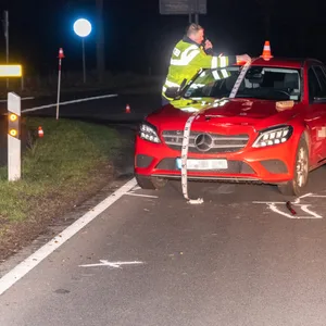 Ein Polizist untersucht den roten Mercedes. Die Straße war über Stunden für die Ermittlungen gesperrt.