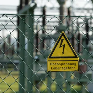 Ein Schild mit der Aufschrift „Hochspannung Lebensgefahr“ hängt an einem Zaun vor dem Gelände des Einspeise-Umspannwerks