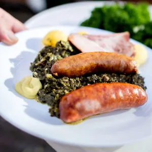 Teller mit Grünkohlgericht: Grünkohl mit Kasseler und Pinkel, Kartoffeln und Senf
