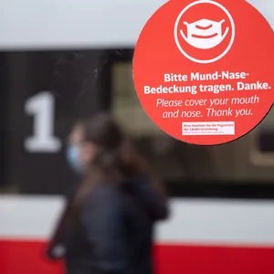Ein Aufkleber mit der Aufschrift „Bitte Mund-Nase-Bedeckung tragen. Danke.“ klebt auf einer Scheibe im Hauptbahnhof.