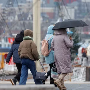 Passanten gehen auf der Hochwasserschutzanlage Baumwall bei wechselhaftem Wetter spazieren.