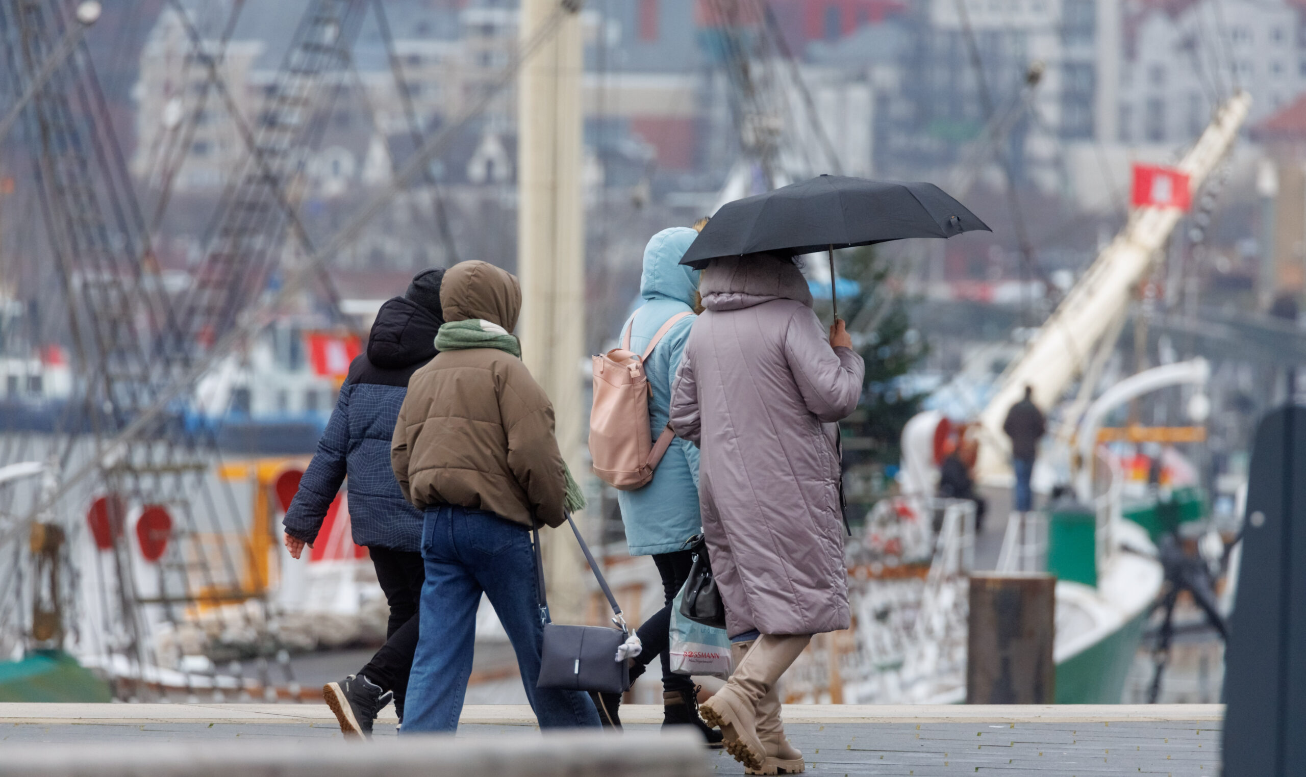 Passanten gehen am Baumwall bei Regenwetter spazieren. (Symbolbild)