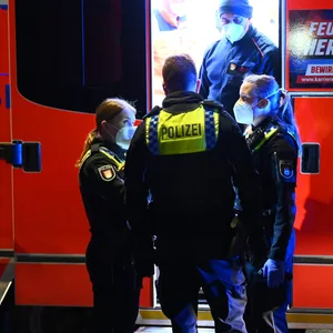 Rettungssanitäter und Polizisten stehen an einem Rettungswagen vor dem Wohnhaus. Bei einem Streit in Hamburg ist dort ein 33-Jähriger mit einem Messer verletzt worden.