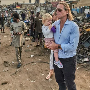 Michel Ruge steht mit seiner Tochter auf dem Arm auf einer Müllhalde.