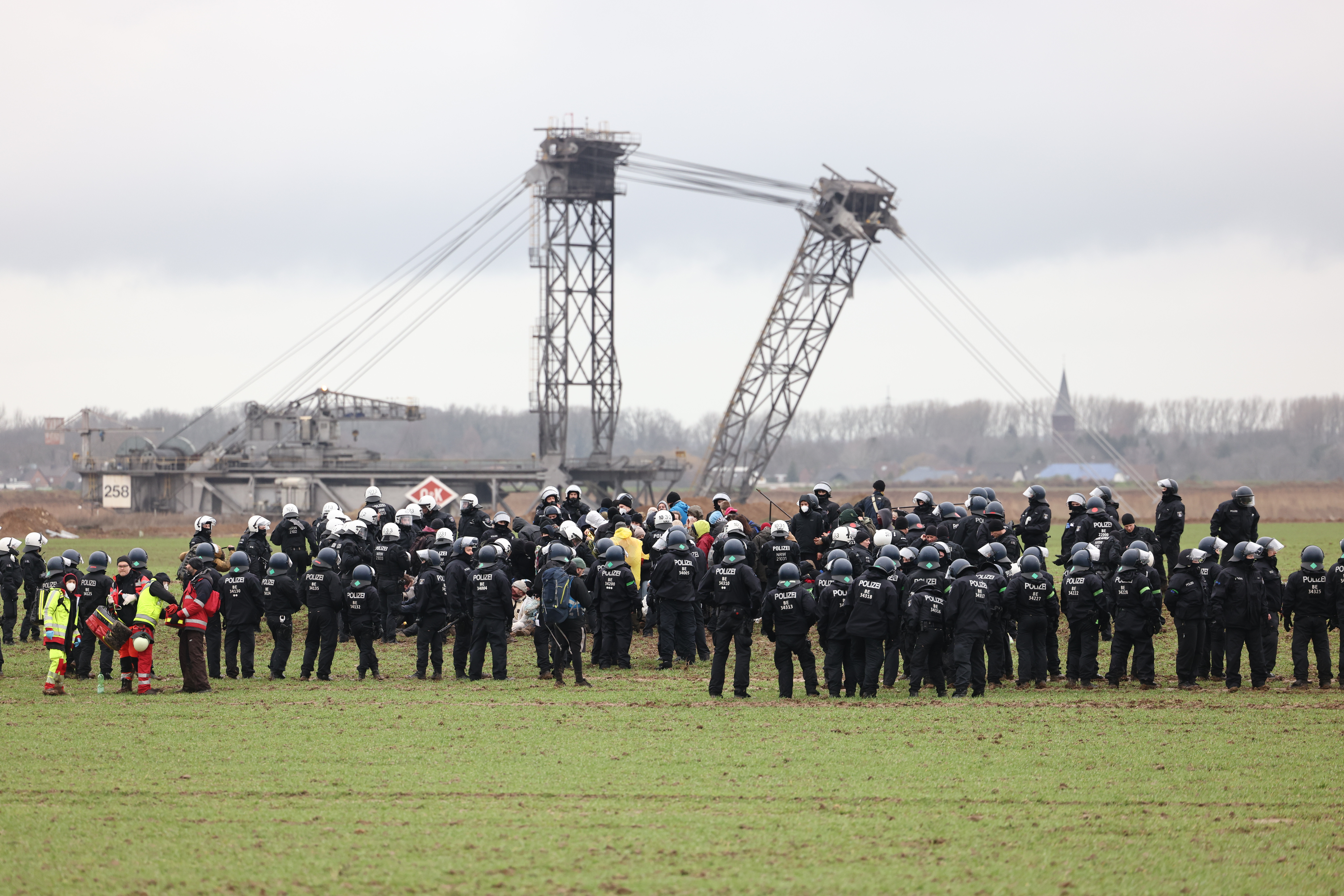 Polizisten und Klimaaktivisten stehen auf einem Feld nahe der Abrisskante von Garzweiler II.