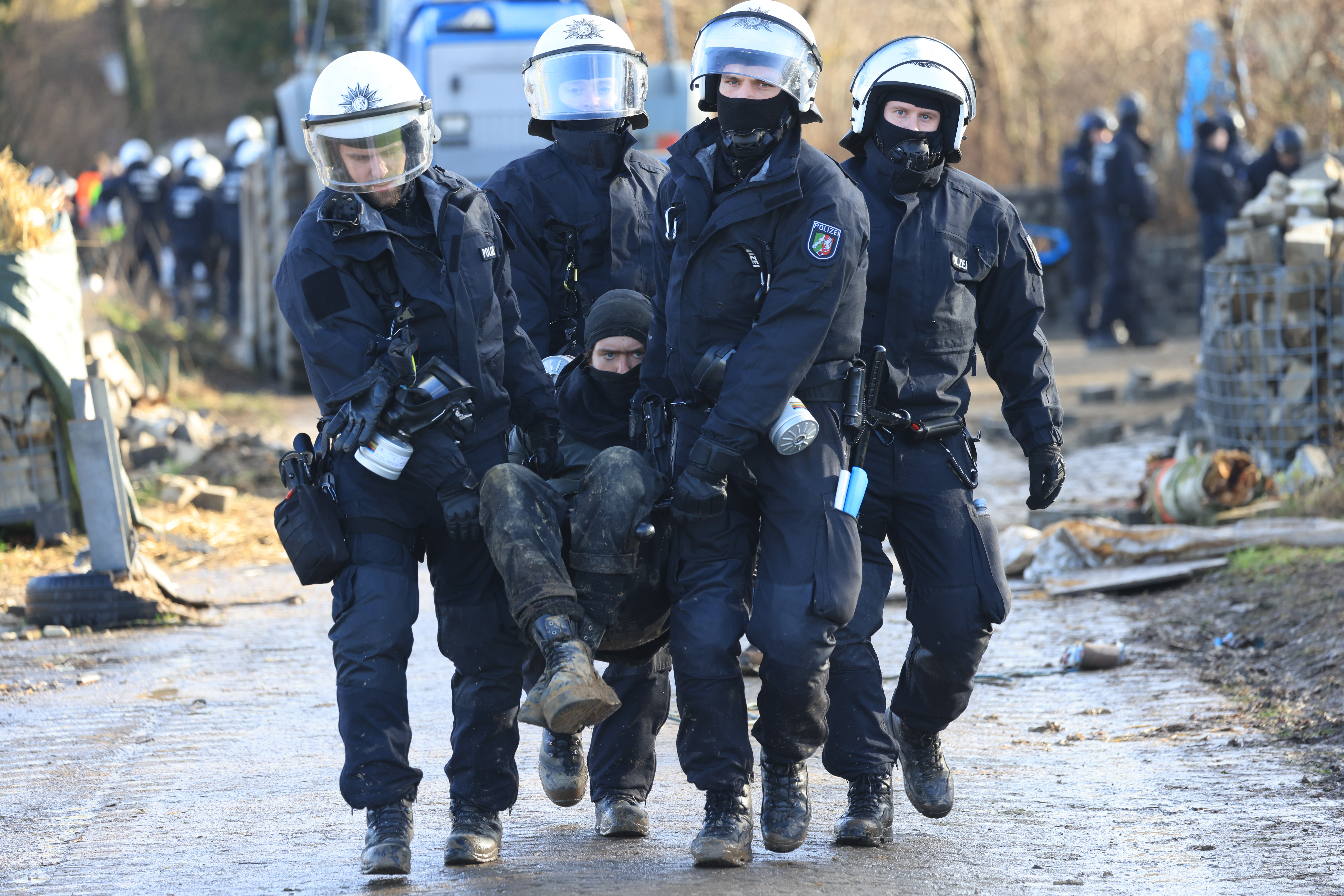 Polizisten tragen einen Klimaaktivisten vom besetzten Braunkohleort Lützerath weg.