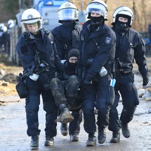 Polizisten tragen einen Klimaaktivisten vom besetzten Braunkohleort Lützerath weg.