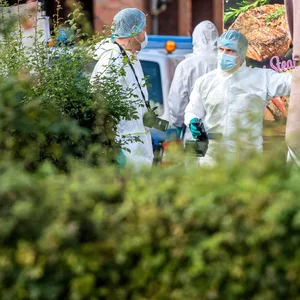 Aufnahme von Polizisten in Schutzanzügen und mit Kameras am Tatort.