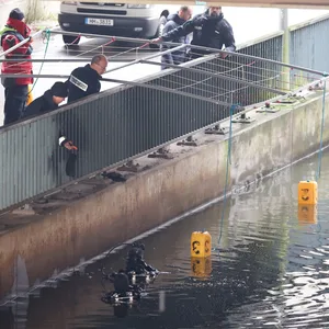 Mit einer Gitterkonstruktion lassen Polizisten in WIlhelmsburg gelbe Bojen zu Wasser. So markieren sie Fundstellen von Körperteilen im Kanal.
