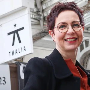 Anders draußen, im Hintergrund das Theater, sie lächelt